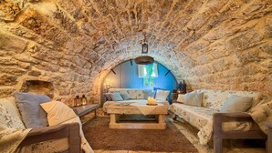 Una stanza accogliente con pareti in pietra, un letto di legno, due divani e un tavolo centrale con candele.