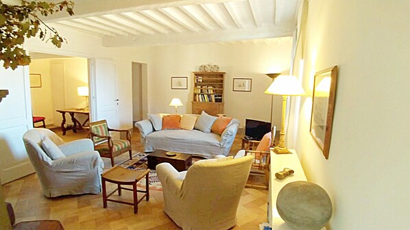 Una sala de estar acogedora con un sofá, sillones, una mesa de centro y una estantería.