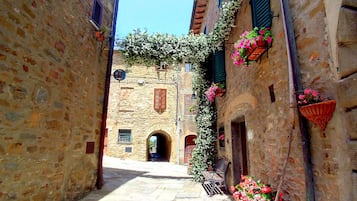 Un vicolo stretto con edifici in pietra, una panchina e fioriere.