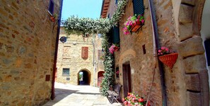 A narrow street with stone buildings, a bench, and flower boxes.
