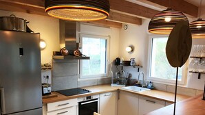 Una cocina moderna con electrodomésticos de acero inoxidable, encimeras de madera e iluminación colgante.