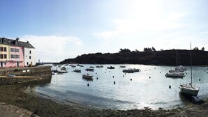 Un puerto con barcos, un muro de piedra y edificios a lo largo de la costa.