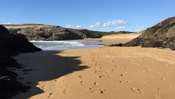 Una playa con acantilados rocosos y cielo despejado.