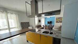 A modern kitchen with a central island, a built-in oven, and a large window with sheer curtains. - Villa With Pool Near The Sea.Syracuse, Plemmirio, Arenella,Fontane Bianche  (Siracusa)