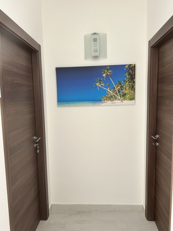 A hallway with wooden doors and a framed picture of a beach scene on the wall. - Villa With Pool Near The Sea.Syracuse, Plemmirio, Arenella,Fontane Bianche (Siracusa)