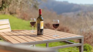 A wooden table with a bottle of wine and two glasses of wine. - Tin mine riverside retreat, log fires, views, wildlife, ruins, pet-friendly (Calstock)