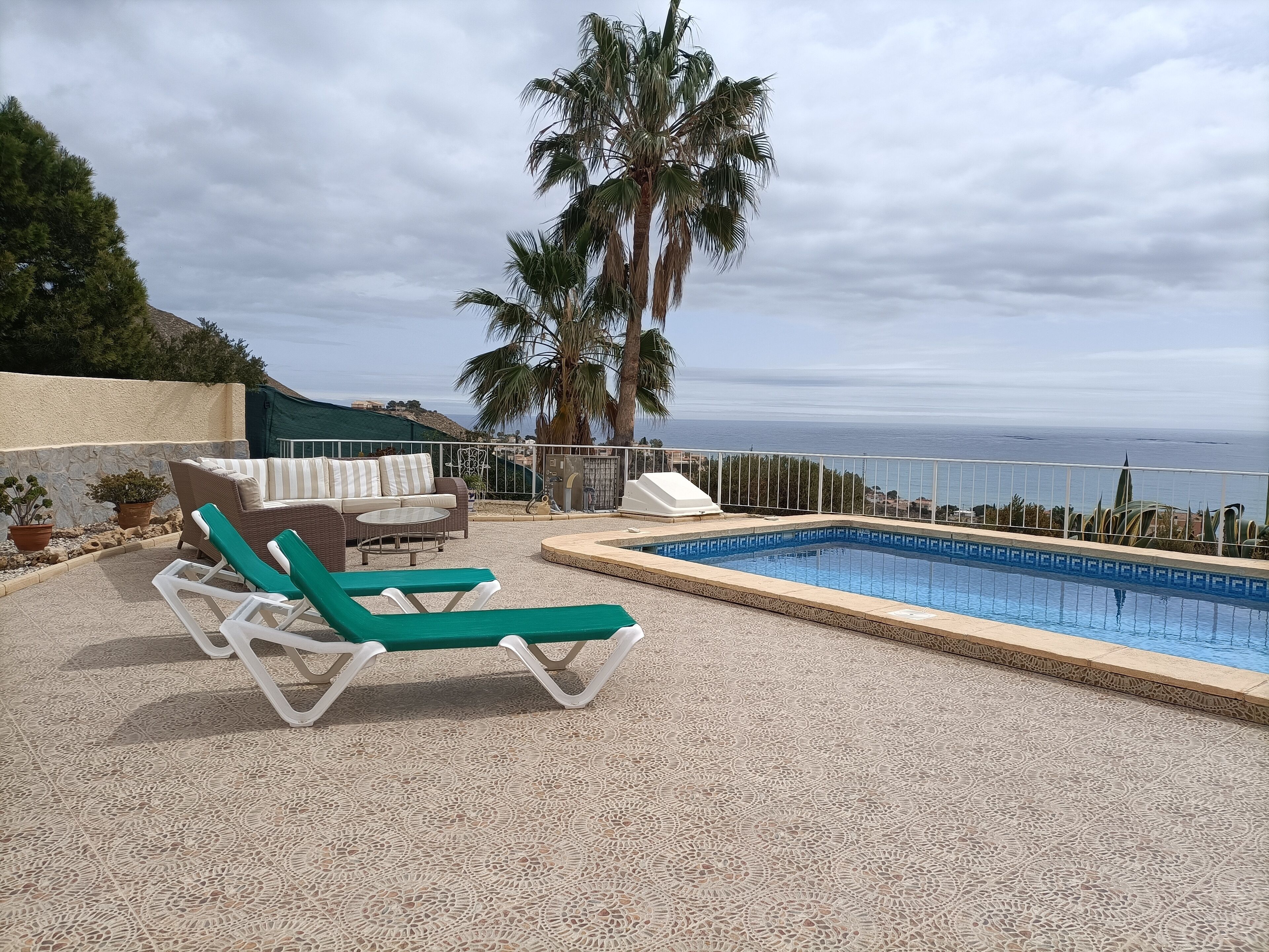 Zona de piscina con sillas de descanso, una piscina pequeña y vista al mar.