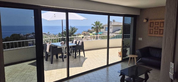 Un balcón con una mesa y sillas, un sofá y vista al mar.