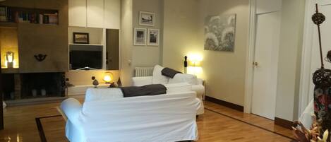Ein Hotelzimmer mit einem großen Bett, einem Kamin, einem Fernseher und einem Bücherregal.