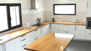 Una cucina moderna con mobili bianchi, un piano di lavoro in legno e un forno integrato.