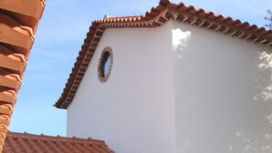 Un edificio con facciata in pietra, tetto a tegole e una finestra circolare.