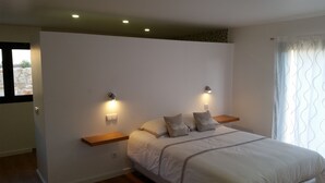 Una camera da letto con un letto, due comodini, una lampada a parete e una finestra con tende.