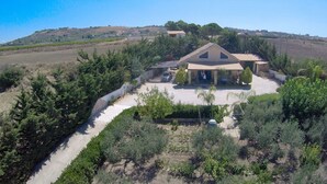 A single-story house with a tiled roof, surrounded by a well-maintained garden and a dirt path leading to the entrance. - Villa with swimming pool a few km from the sea Selinunte (Partanna)
