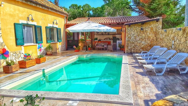 A swimming pool with lounge chairs, a stone wall, and a patio area with potted plants. - Villa with swimming pool a few km from the sea Selinunte (Partanna)