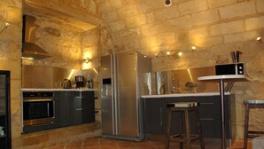 A kitchen with a stone wall, stainless steel appliances, and a bar area. - Great warm T2 68 M2, atypical, in the historic center (Bordeaux)