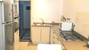 Una cocina compacta con refrigerador, horno, microondas, pileta y estufa a gas.