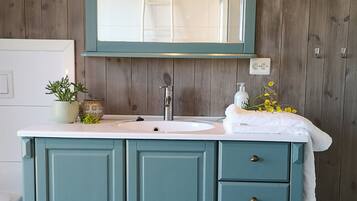 A bathroom with a teal vanity, a mirror, and a sink.