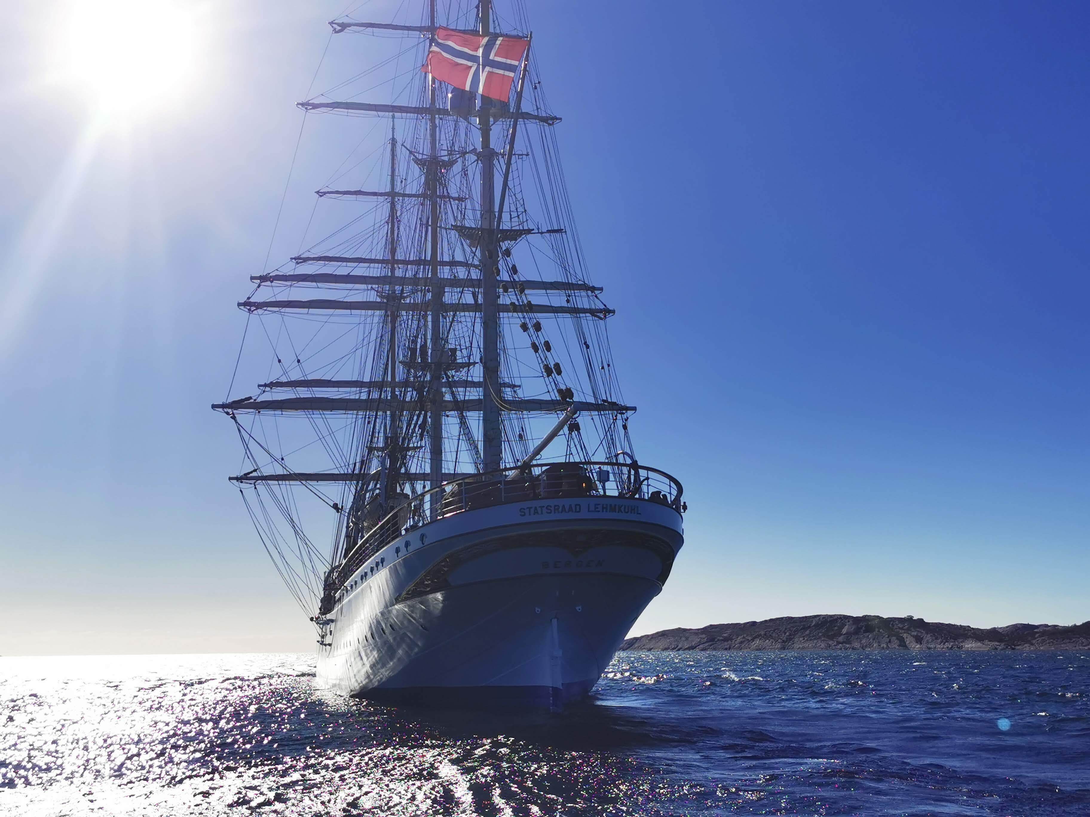 Un grand voilier à plusieurs mâts et avec un gréement complexe, naviguant sur une mer calme sous un ciel dégagé.