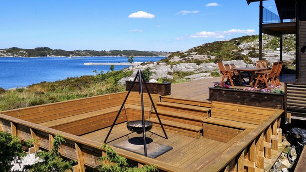 A wooden deck with a table and chairs overlooking a body of water.