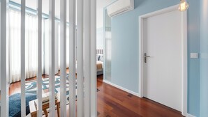 A room with a wooden floor, a white door, and a blue wall. - Victoria Project - Apartment II - Private Parking (Porto)