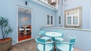 A patio with a round table and chairs, a potted plant, and a door leading to an interior space. - Victoria Project - Apartment II - Private Parking (Porto)