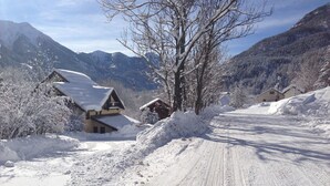 Una strada innevata con case e montagne sullo sfondo.