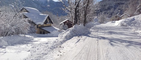 Una strada innevata con case e montagne sullo sfondo.