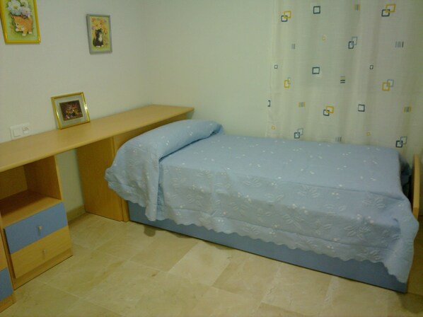 A small bedroom with a single bed, a desk, and a chair.