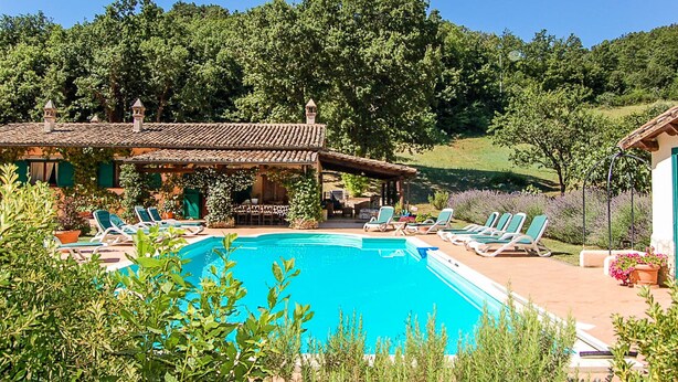 Zona de piscina amb gandules i un edifici amb teulada enrajolada.