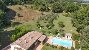 Una vila amb piscina, envoltada d'un jardí exuberant i un paisatge amb turons.