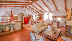 Àmplia zona d'estar amb un sostre alt, bigues de fusta, sofà, taula de dinar i zona de cuina amb un frigorífic vermell.