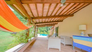 Un porxo cobert amb un hamaca, mobles d'exterior i vistes a una piscina.