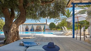 A poolside area with lounge chairs, a covered seating area, and a large tree providing shade. - Blue House with pool. Paradise between sky and sea  (Trabia)
