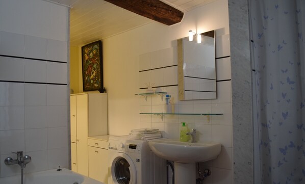 Un baño con lavadora, lavamanos y espejo.