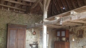 A rustic room with stone walls, wooden beams, a large wooden wardrobe, a sewing machine, and a wooden cabinet. - Beautiful family home (Vauban)