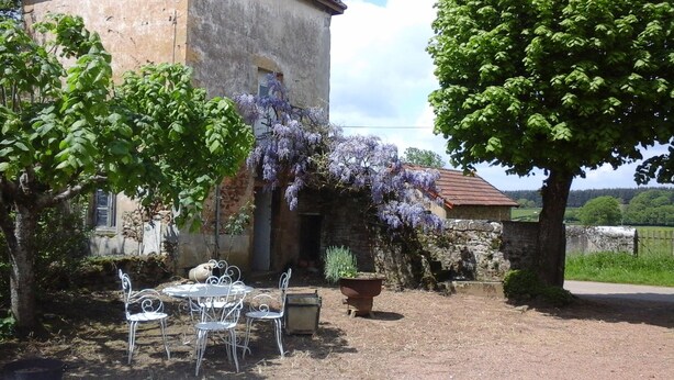 A rustic stone building with a garden patio featuring metal chairs and a table. - Beautiful family home (Vauban)