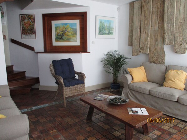 Una sala de estar con una silla de mimbre, un sofá, una mesa de centro y una escalera.
