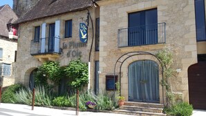 A stone building with a balcony, a large window with a curtain, and a sign reading "la Plume d'Oie". -  Charming riverside stone built  property in Perigord (La Roque-Gageac)