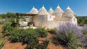 Un bâtiment en pierre, doté de toits coniques, entouré de verdure et de plantes de lavande.