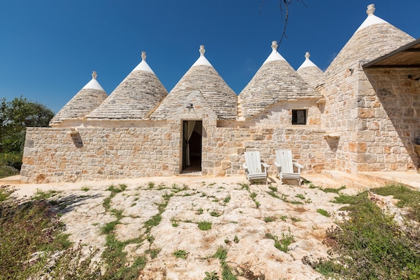 A stone building with multiple conical roofs and a small door.