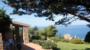 Eine Terrasse mit Sitzgelegenheiten im Freien, eine Steinmauer und Blick auf das Meer.