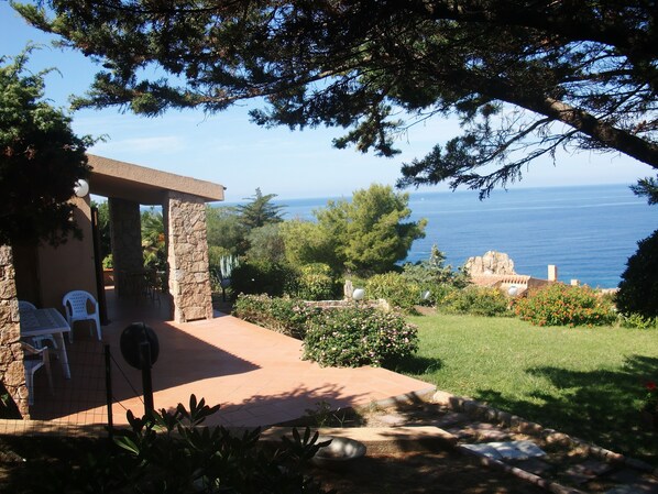 Un patio con mobiliario exterior, una pared de piedra y vistas al mar.