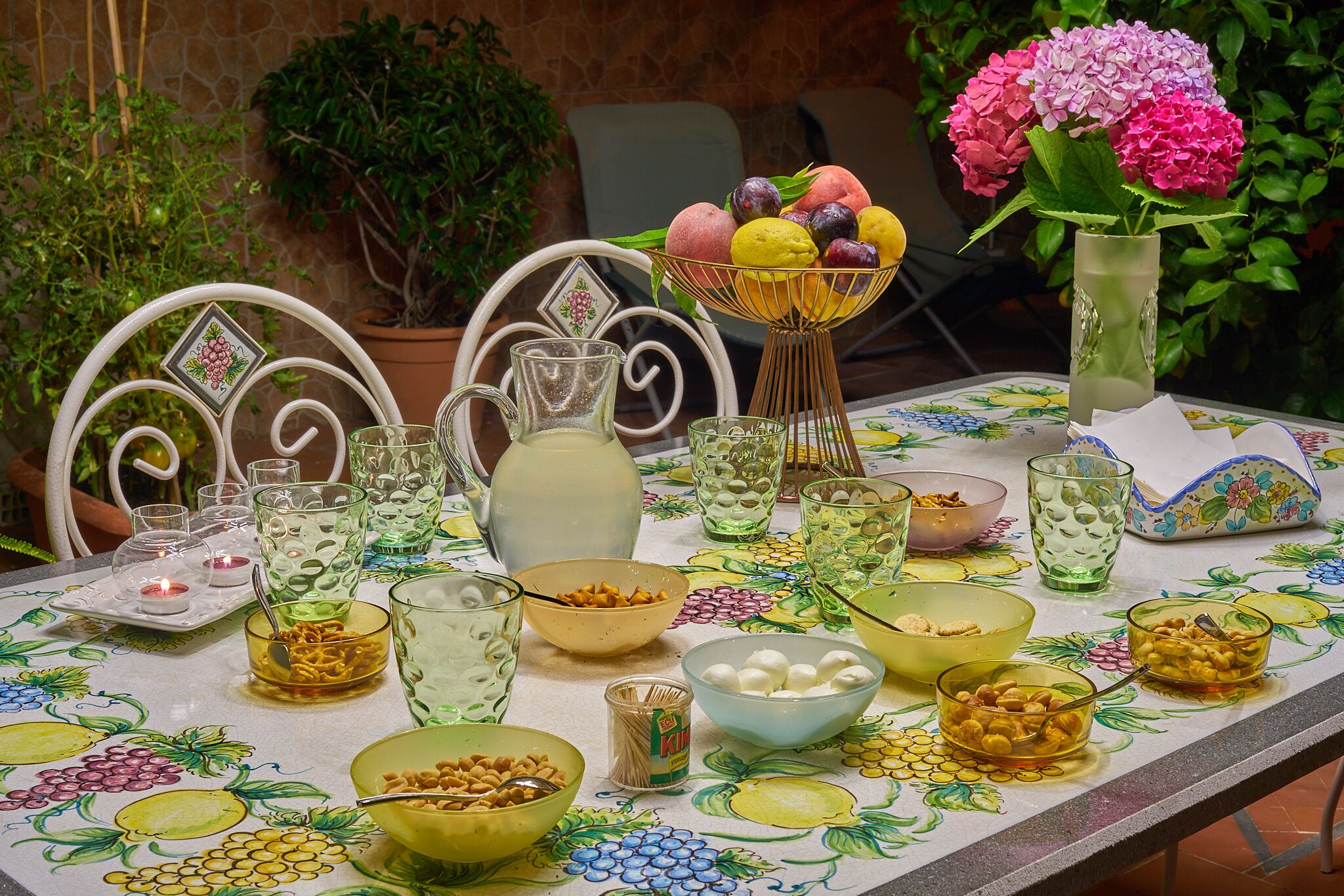 Una mesa dispuesta con diferentes vasos, recipientes y un frutero.