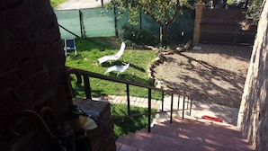 Una escalera que lleva a una zona con césped, una cerca y una puerta al fondo.