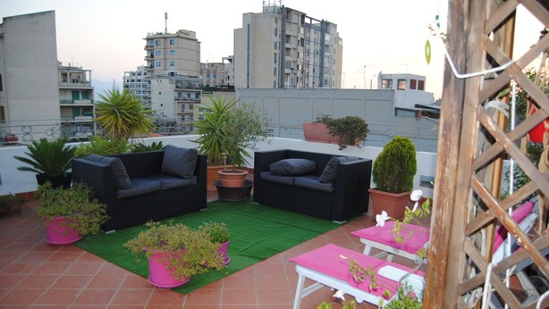 Une terrasse sur le toit, aménagée avec du mobilier d’extérieur, des plantes en pot et offrant une vue sur le paysage urbain.