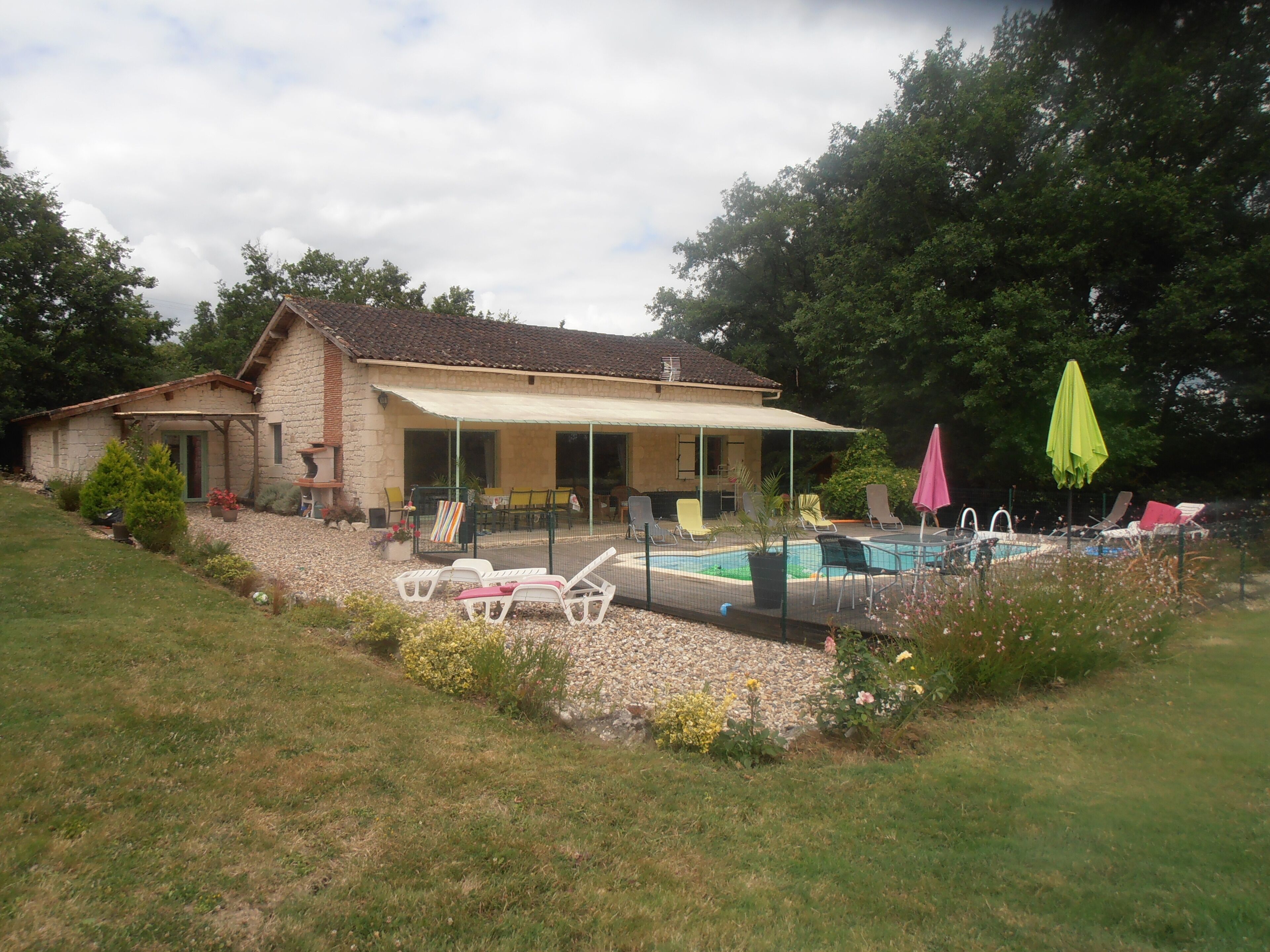 A house with a swimming pool, outdoor seating, and a garden.