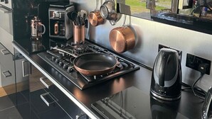 Una cocina moderna con estufa a gas, utensilios de cocina de cobre y hervidor.