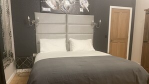 Un dormitorio con una cama grande, un cabecero, un reloj de pared y una puerta.