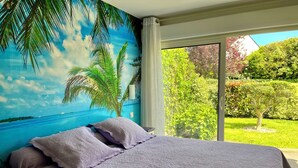 A bedroom with a bed, a nightstand, and a view of a garden through a large window. - House / Villa - LA BAULE-ESCOUBLAC (La Baule-Escoublac)