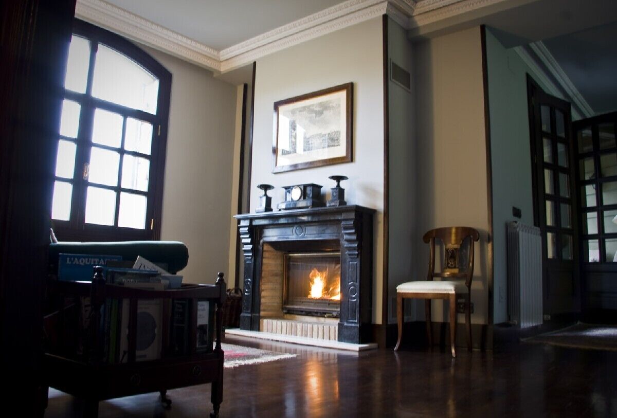 A room with a fireplace, a bookshelf, and a chair.